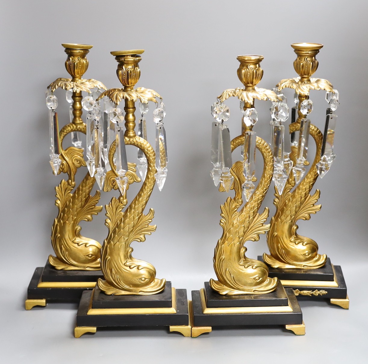 A set of four bronze dolphin and lustre candlesticks, 42 cms high